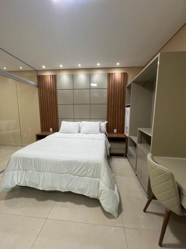 une chambre avec un grand lit blanc et une chaise dans l'établissement Barra Gold Hotel, à Barra Do Rio Grande