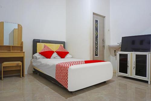 a bedroom with a bed with red pillows and a tv at Hotel O Pondok Feby Makassar in Makassar