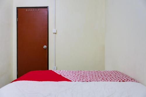 a bedroom with a bed with a red and white blanket at Hotel O Ringin Pitu 1 Syariah in Jodoh