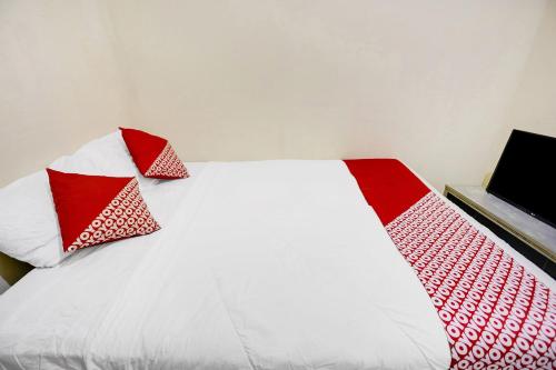 a white bed with red and white pillows on it at Hotel O Ringin Pitu 2 SyariahNearAnugrah Sinar Lautan in Jodoh