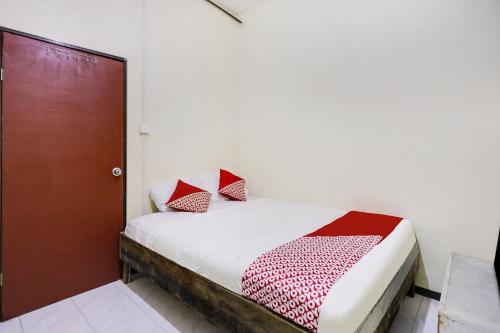 a bedroom with a bed with red and white pillows at Hotel O Ringin Pitu 2 SyariahNearAnugrah Sinar Lautan in Jodoh