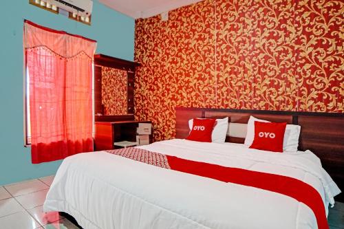a bedroom with a large bed with red and gold wallpaper at OYO 91418 Kantil Homestay Syariah in Sunggal