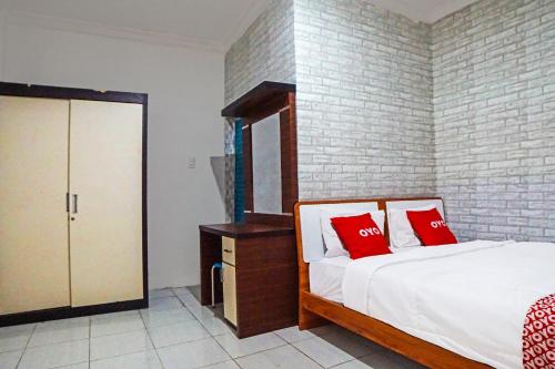 a bedroom with a bed with red pillows on it at OYO 91418 Kantil Homestay Syariah in Sunggal