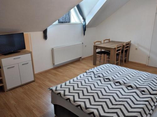 a bedroom with a bed and a table and a desk at Apartments Košević in Osijek