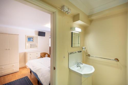 ein Badezimmer mit Waschbecken und Bett in der Unterkunft Mermaid - Pet Friendly Self Catering Holiday Cottage Hayle in Hayle