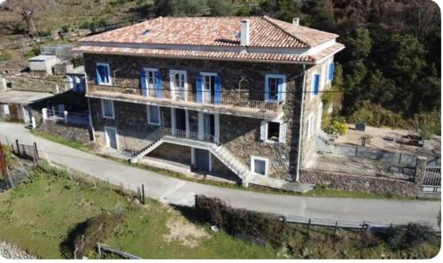 une grande maison avec des fenêtres bleues sur une colline dans l'établissement Appartement Saltare Rivière & maquis, à Manso