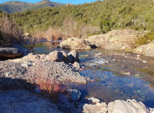une rivière avec des rochers et des montagnes en arrière-plan dans l'établissement Appartement Saltare Rivière & maquis, à Manso