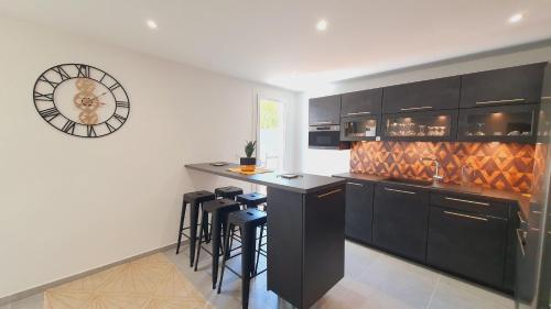 une cuisine avec un bar avec des tabourets et une horloge dans l'établissement T3 double terrasses CLIM WIFI en Centre-ville - ROSSIconciergerie - Linge inclus, à La Grande Motte