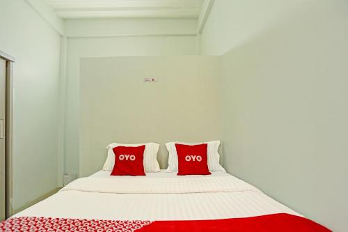 a white bed with two red pillows on it at OYO 91434 Cek@n Guest House in Banda Aceh