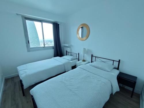 - 2 lits dans une chambre avec un miroir et une fenêtre dans l'établissement Cozy 1 bedroom Apartment La Defense, à Courbevoie