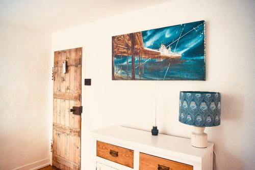 a table with a lamp and a painting on a wall at Beautiful Old Cottage near the Seafront in Eastbourne