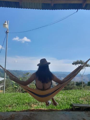 a woman sitting in a hammock with a hat at Econative Baru Toucan Cabin con vista al bosque de Platanillo in Platanillo