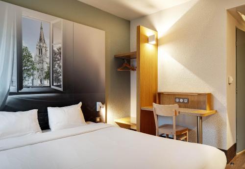 a hotel room with a white bed and a chair at B&B HOTEL Lille Tourcoing Centre in Tourcoing
