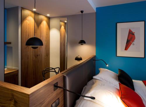 a bedroom with a bed with a blue wall and a mirror at Hostellerie Du Chapeau Rouge in Dijon