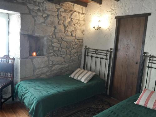 a bedroom with a bed and a stone wall at La casita de piedra in Porto do Son