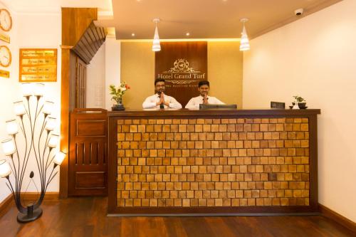 two men sitting at a bar in a restaurant at Hotel Grand Turf By GSP in Nuwara Eliya