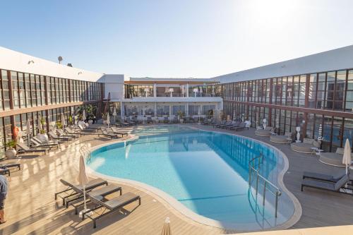 a large swimming pool in a building with chairs at Seth Port Ciutadella in Ciutadella