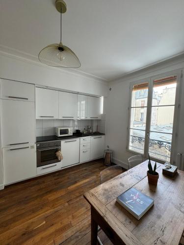 une cuisine avec des armoires blanches et une table en bois dans l'établissement Appartement situé en plein coeur de Paris, à Paris