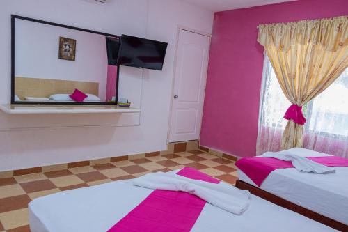 two beds in a room with pink walls and a window at OYO Hotel Marías,Aeropuerto Internacional de Chetumal in Chetumal