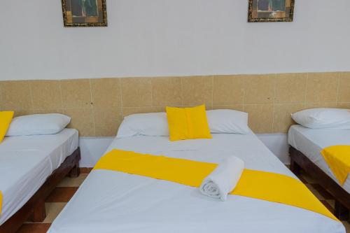 a room with two beds with yellow and white sheets at OYO Hotel Marías,Aeropuerto Internacional de Chetumal in Chetumal