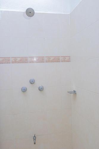 a bathroom with a shower with white tiles at OYO Hotel Marías,Aeropuerto Internacional de Chetumal in Chetumal
