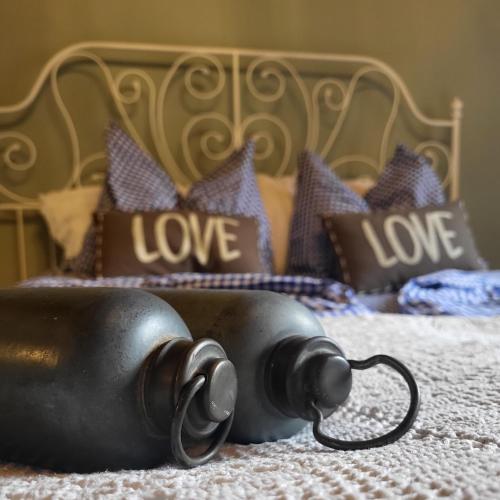 a black tea pot on a bed with love pillows at Sachserhof Ferienwohnungen in Sachsenburg in Sachsenburg