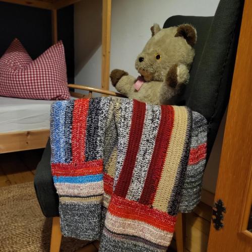 a teddy bear sitting on a chair with a blanket at Sachserhof Ferienwohnungen in Sachsenburg in Sachsenburg