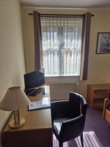 a desk with a computer and a chair and a window at Hotel Müritzlicht in Waren