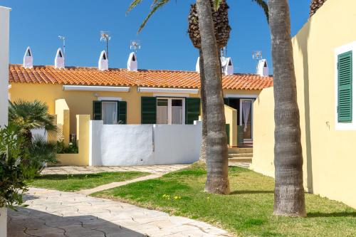 a house with a white fence and palm trees at Las siete palmeras - ciudadela in Cala en Blanes