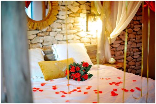 a bed with a bouquet of red roses on it at Duplex Safari jusqu'à 4 personnes, Spa XXL, day use, cinéma, cascade et lit sous les arbres in Bourgoin