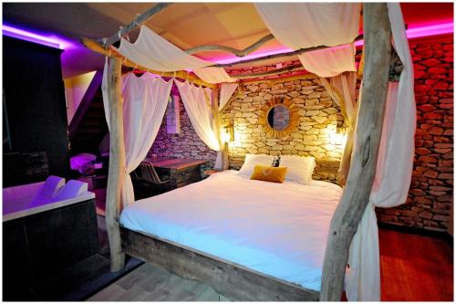 a bedroom with a canopy bed in a stone wall at Duplex Safari jusqu'à 4 personnes, Spa XXL, day use, cinéma, cascade et lit sous les arbres in Bourgoin