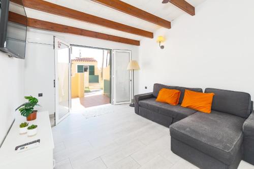 a living room with a gray couch and orange pillows at Las siete palmeras - ciudadela in Cala en Blanes