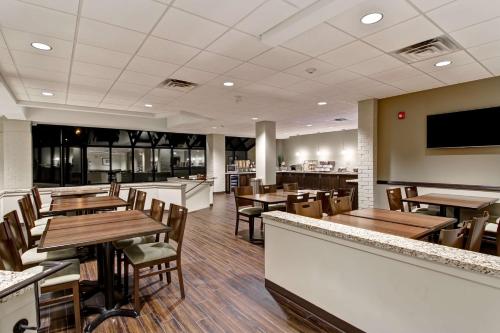un restaurant avec des tables et des chaises en bois ainsi qu'un bar dans l'établissement Best Western London Airport Inn & Suites, à London
