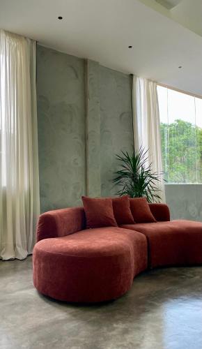 a red couch in a living room with windows at BaBa Boutique House Langkawi in Pantai Cenang
