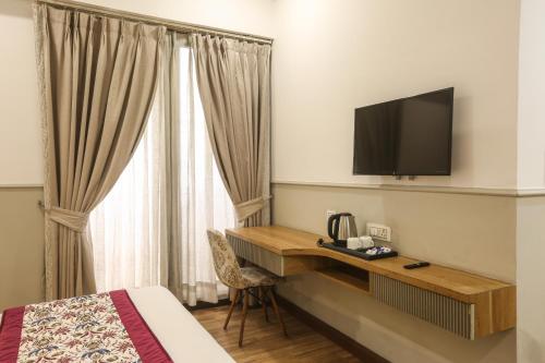 a hotel room with a desk and a television at Hotel Emerald Suites & Banquet By Aura in Noida