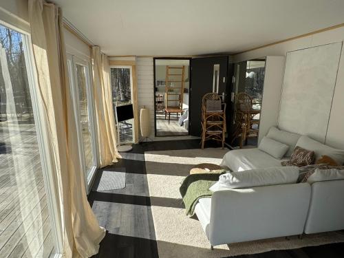 a living room with a white couch and a television at Cabin in the forest with Spa bath in Västra Torup