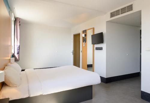 a white bedroom with a white bed and a tv at B&B HOTEL Lieusaint Carré Sénart in Lieusaint