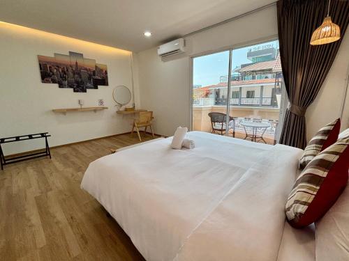 a bedroom with a large white bed and a large window at Charm Hostel at Pratumnak in Pattaya South