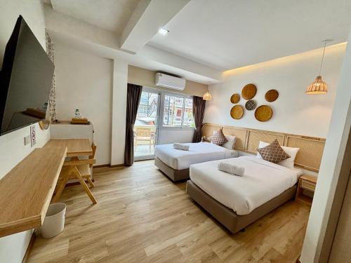 a hotel room with two beds and a desk at Charm Hostel at Pratumnak in Pattaya South