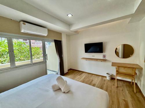 a bedroom with a white bed and a television at Charm Hostel at Pratumnak in Pattaya South