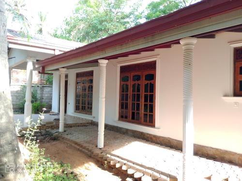a white house with columns and a door at Thanumi Polonnaruwa in Polonnaruwa