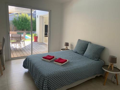 una camera da letto con un letto con due cuscini rossi sopra di Villa 12 personnes piscine chauffée et jacuzzi a Capbreton