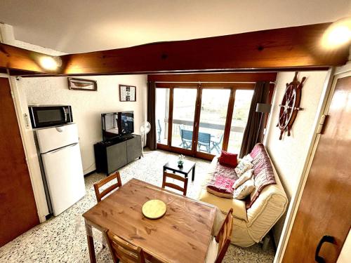 Il comprend un petit salon avec une table et une cuisine. dans l'établissement Appartement 2 pièces proche plage, balcon, parking - FR-1-229C-107, à Port-la-Nouvelle