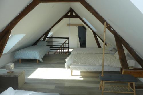 a attic room with two beds and a chair at La Maison de Mémé gîte 14 pers aux portes de la Baie de Somme in Tours-en-Vimeu