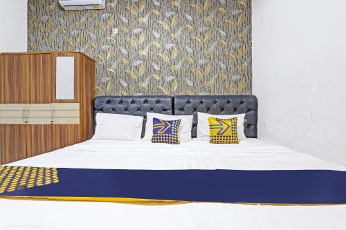 a bed with a black headboard and two pillows at SPOT ON 91521 Mayong Guesthouse in Jepara