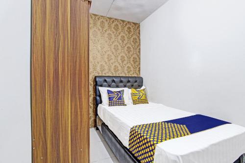 a small bedroom with two beds and a closet at SPOT ON 91521 Mayong Guesthouse in Jepara