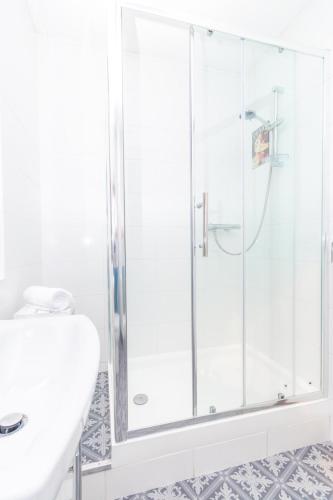 a white bathroom with a shower and a sink at Central Dundee 2 Bed Apt near V&A Museum & City Attractions in Dundee