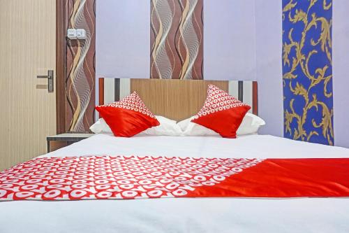 a bed with red and white pillows on it at Collection O 91488 Hotel Lingkarsut Jeneponto Near Patung kuda, Jeneponto in Pannara