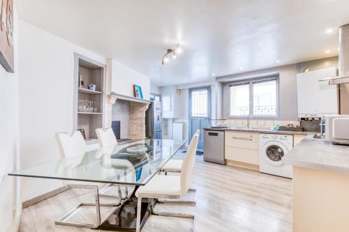une cuisine avec une table en verre et des chaises blanches dans l'établissement Maison De Village De 80m2, à Lansargues
