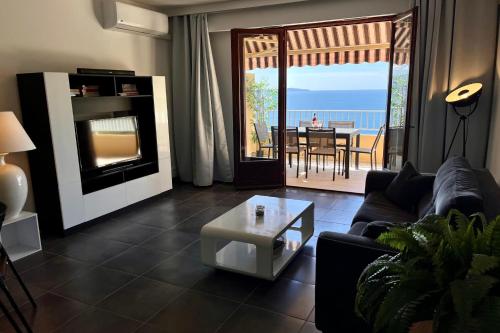un salon avec un canapé et une table avec vue dans l'établissement Dany - Apartment with large balcony and sea view, à Ajaccio